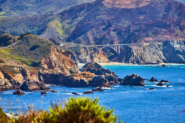 View of Bixby Bridge on west coast from distance surrounded by mountains