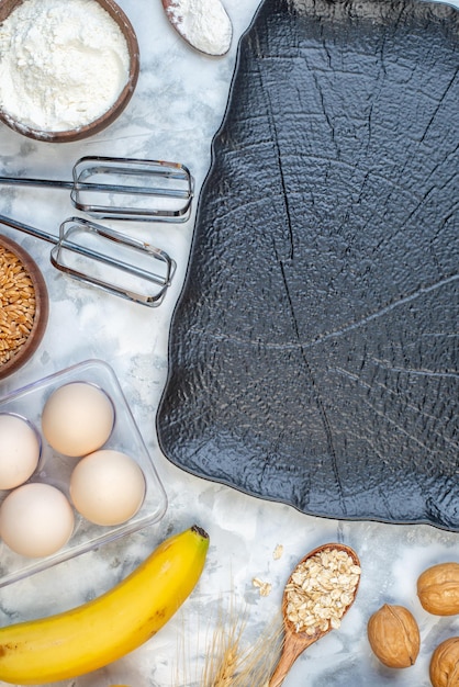 Above view of black tray and flour fresh bananas eggs brown rice on ice surface