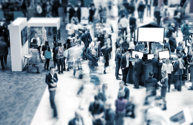 Photo view of blurred crowd on a exhibition with trade fair booths. copyspace for your individual text.