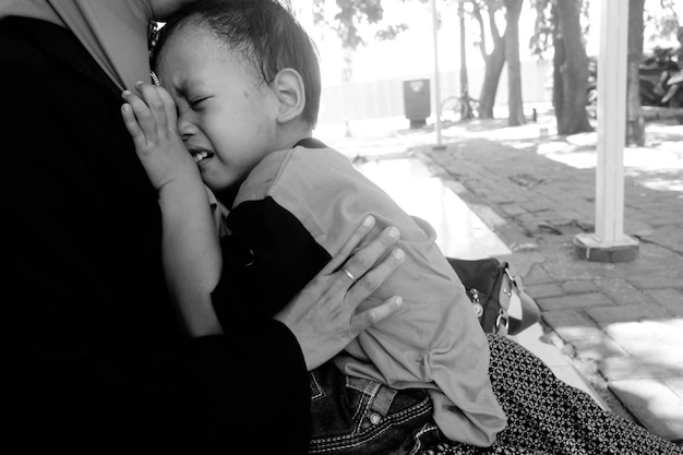 Photo view of boy crying and hugging mommy