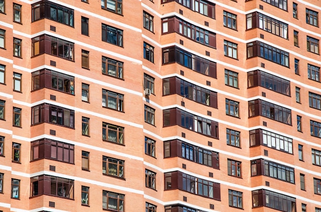 View of brick wall of red contemporary apartment building with windows and balconies