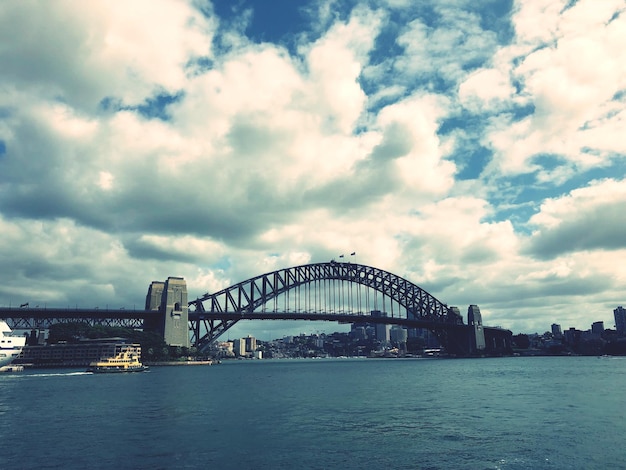 Photo view of bridge over river against cloudy sky