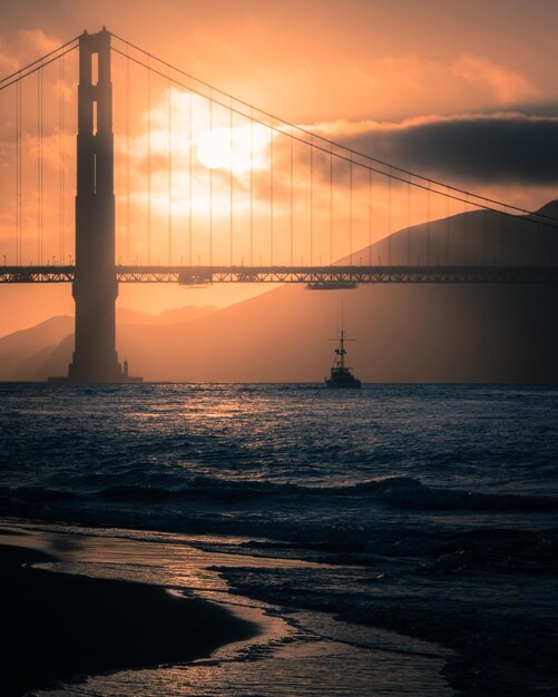 Photo view of bridge over sea against cloudy sky during sunset