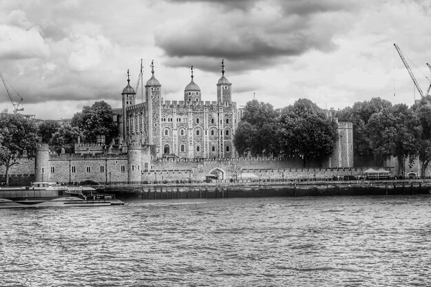 Photo view of buildings by river against cloudy sky