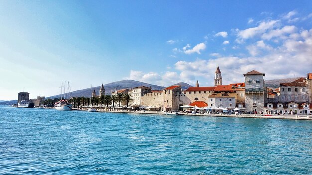 Photo view of buildings by sea against blue sky