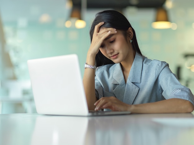 view of businesswoman feeling stressed while working with laptop on the table in office room