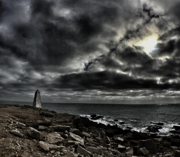 View of calm beach below cloudy sky