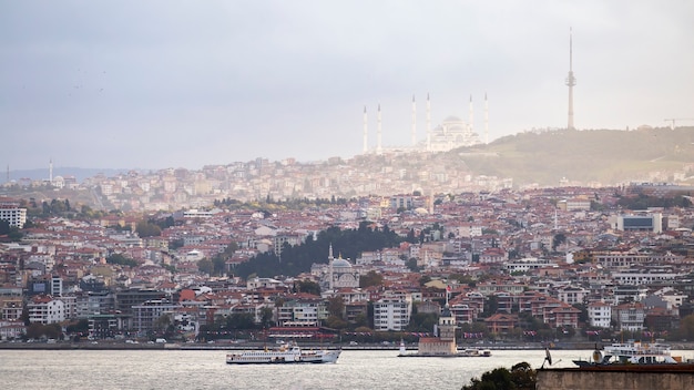 Vista della moschea camlica situata su una collina con edifici residenziali, lo stretto del bosforo, la nave galleggiante e la torre di leander, istanbul, turchia