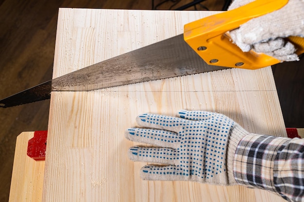 Above view of carpenter hands sawing wooden board