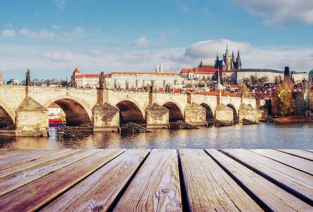 View of the Charles Bridge which crosses the River Vltava and wooden pier in foreground