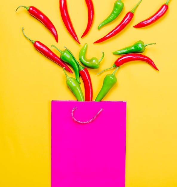 Above view at Chili pepper and shopping bag on yellow background