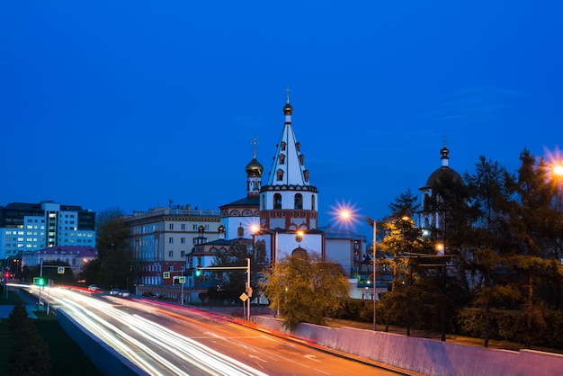 Photo view of the christian church through the lines from passing cars at night against a blue sky surroun