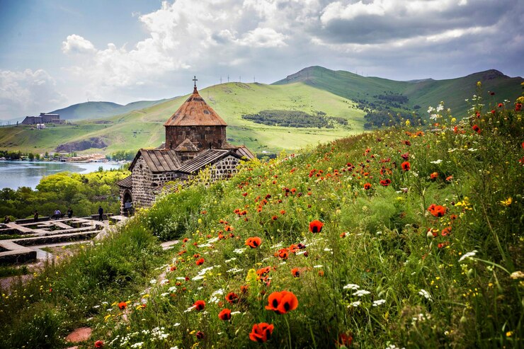 Photo a view of a church in the mountains with flowers in the foreground armenia