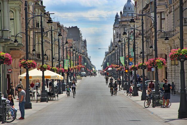 View of city street with many flowers and people riding bicycles City life in Lodz Central street