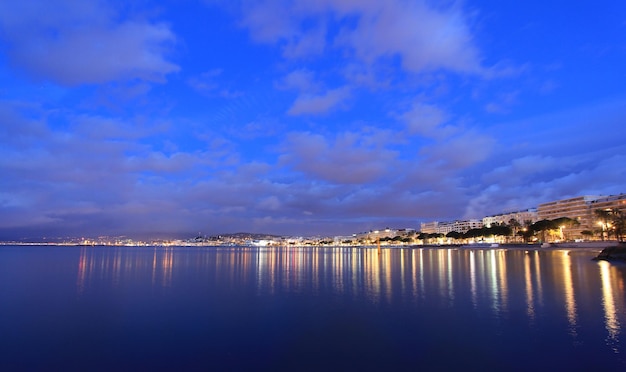 View of city at waterfront against cloudy sky