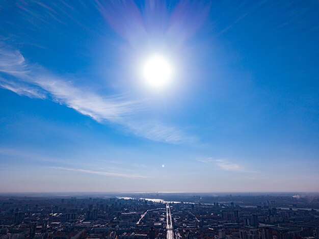 夏の日の太陽と雲のない空から見た、川の高層ビル、メインストリートの木々、屋根のある街の眺め