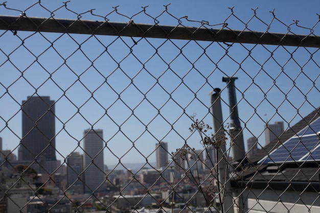 Photo view of cityscape through chain link fence