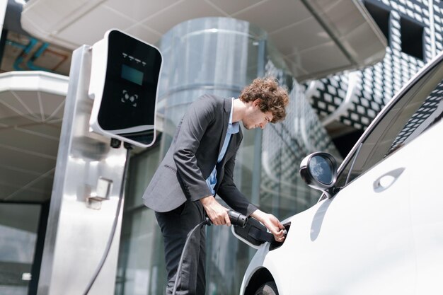 以下のビューのクローズ アップ プログレッシブ ブラック スーツのビジネスマンは、EV 車のバッテリーを充電します。