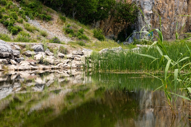 View of the coastline of a mountain lake in the foreground with large stones and reflection in the water. Scenery.