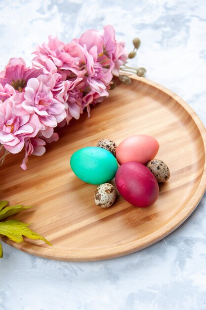 above view colored easter eggs on cutting board on white surface