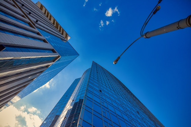 View of the commercial glass business skyscraper tower against the blue sky -shot from bottom to up