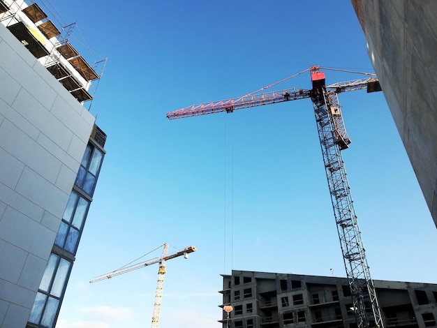 View of a construction site on a sunny day. The construction of residential buildings using tower cranes.