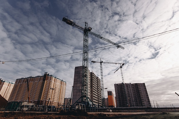 Photo view of the construction site with cranes and high-rise residential buildings.