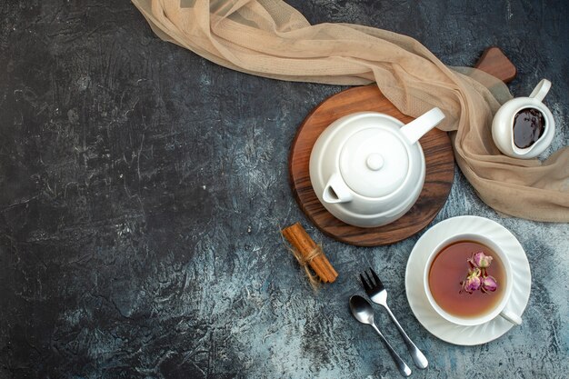 Above view of a cup of black tea and kettle on wooden board on ice background