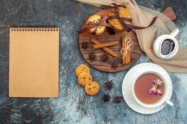 Sopra la vista di una tazza di tè nero impilati con biscotti alla cannella e lime per notebook su sfondo di ghiaccio