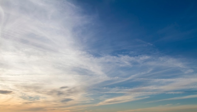 View of a deep blue sky with clouds approaching sunset.