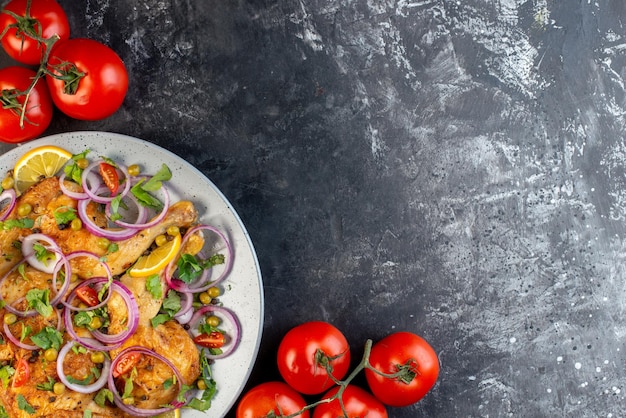 Above view of delicious dinner fried chicken dish with various spices and foods tomatoes with stems on the right side on dark color background