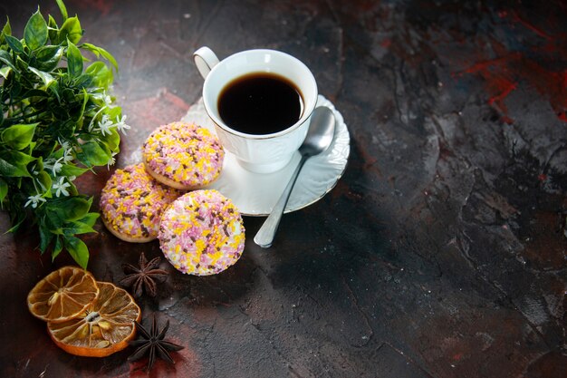 Sopra la vista di deliziosi biscotti di zucchero e una tazza di caffè con fettine di limone essiccate su sfondo scuro di colori misti