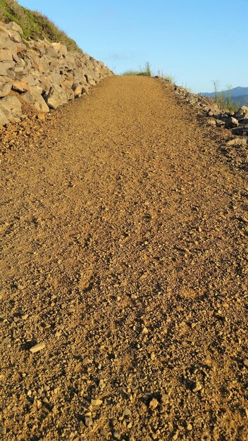 View of dirt road on field against sky