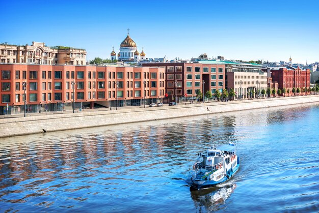 View of the dome of the Cathedral of Christ the Savior, houses on Prechistenskaya embankment and a ship on the Moskva River in sunny morning Moscow