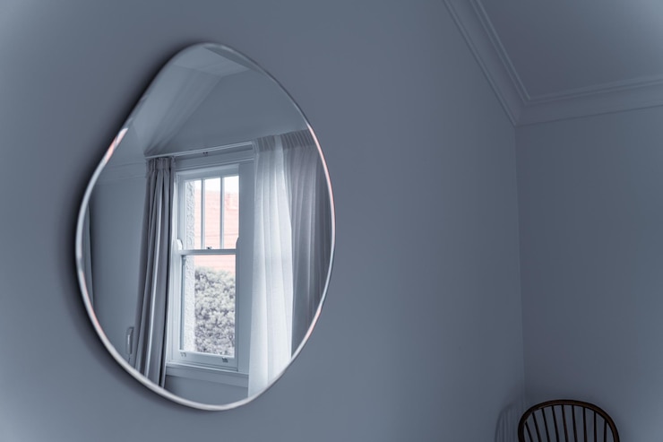 Photo view of a dropshaped mirror on the white wall of a room