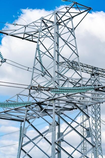 View of electric supply station dark shadow of high voltage\
line high voltage pylons against blue sky background