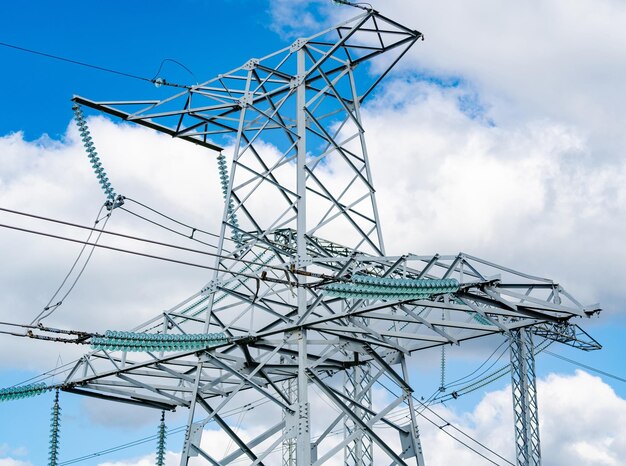 View of electric supply station dark shadow of high voltage
line high voltage pylons against blue sky background