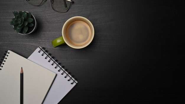 Above view empty notebooks glasses and cup of coffee on black table