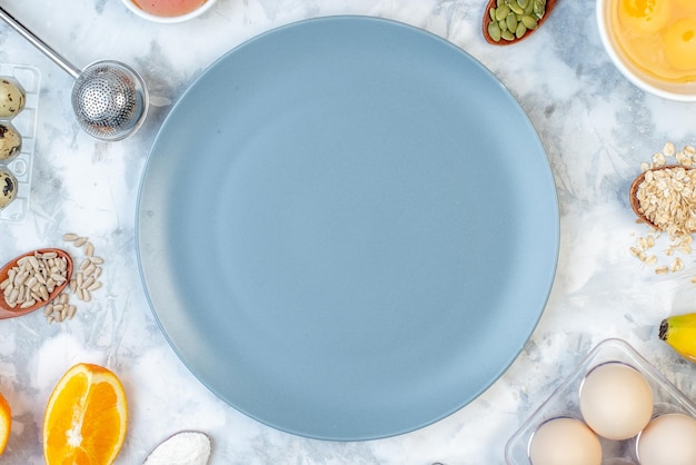 Above view of empty plate and ingredients for the healthy food set on white blue table