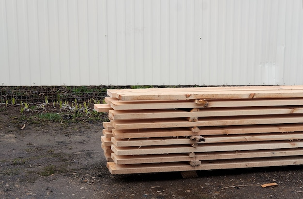 View of ends of stacked edged larch boards with beveled edge, planken for construction of fence or cladding house, timber prepaired for building