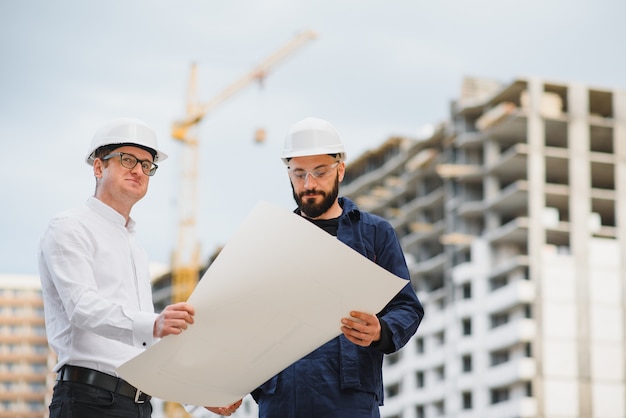 View of an Engineer and worker checking plan on construction site