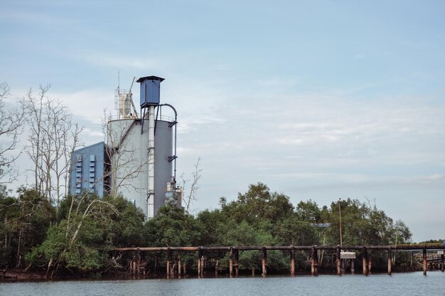 View of factory by river against sky