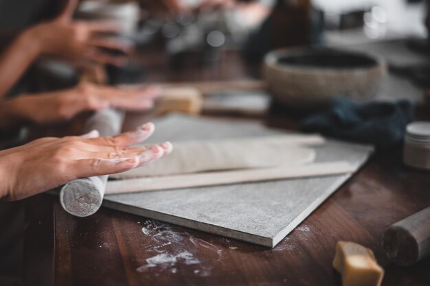 View of female hands works with clay makes future ceramic plate\
ceramic artist makes classes of hand building in modern pottery\
workshop creative people handcrafted design