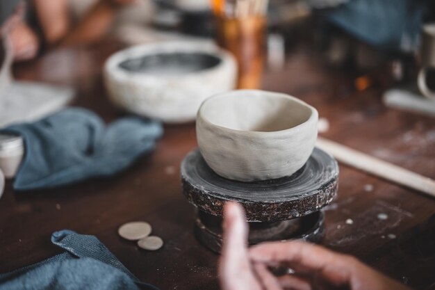 View of female hands works with clay makes future ceramic plate\
ceramic artist makes classes of hand building in modern pottery\
workshop creative people handcrafted design