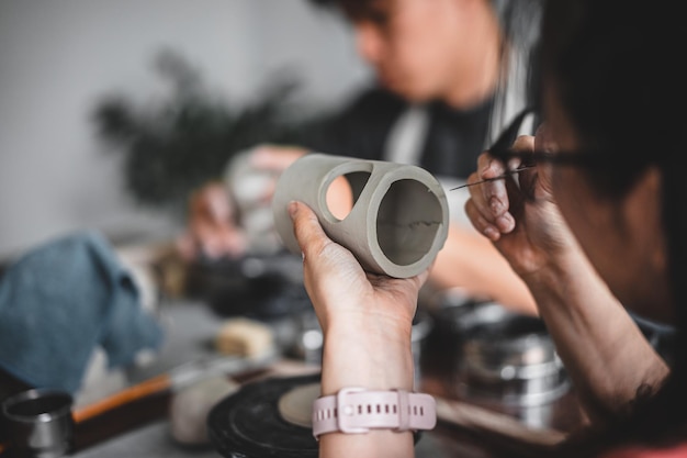 View of female hands works with clay makes future ceramic plate\
ceramic artist makes classes of hand building in modern pottery\
workshop creative people handcrafted design