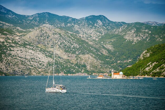 View of a floating white yacht near Our Lady of the Rocks in the Bay of Kotor