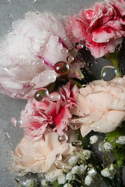 View of flowers behind glass with water drops