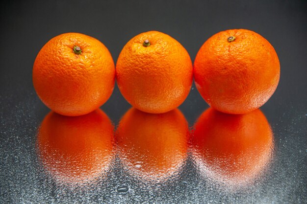 Above view of fresh oranges standing side by side on light on black background with free space