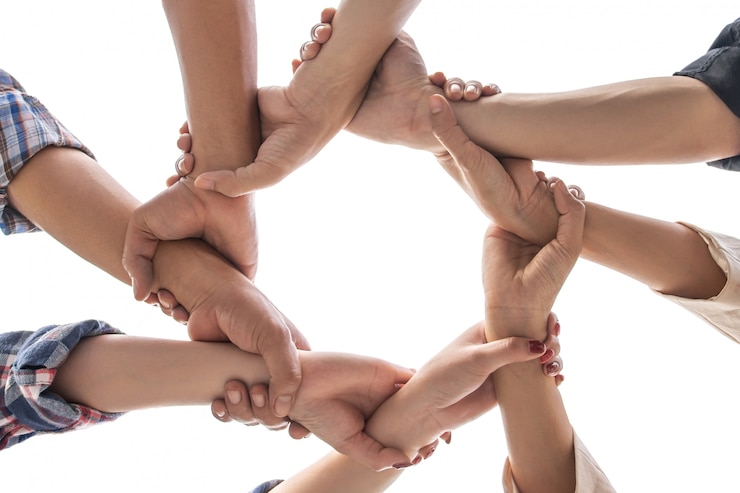 Photo under view friendship people partnership teamwork crossed hands on white background 