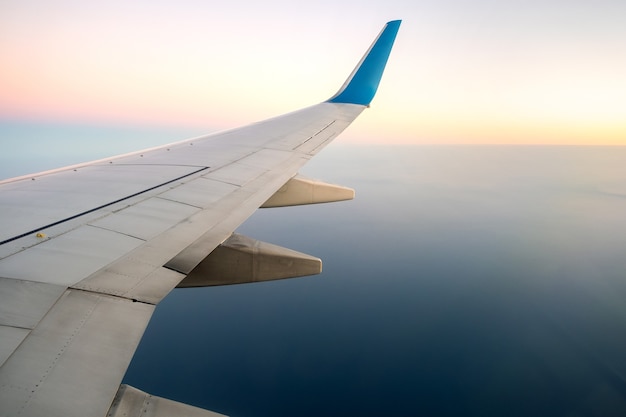 View from airplane on the aircraft white wing flying over ocean landscape in sunny morning